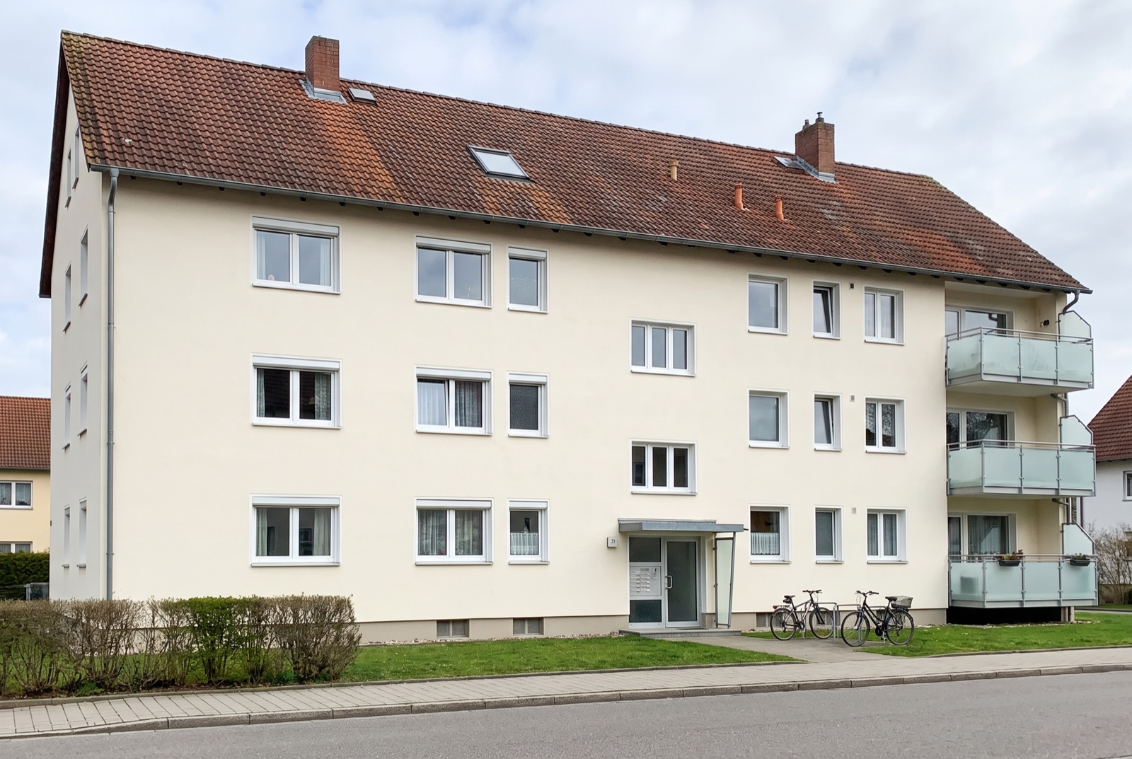 Dasselbe Mehrfamilienhaus mit ausgeblichenem, fleckigem Altdach