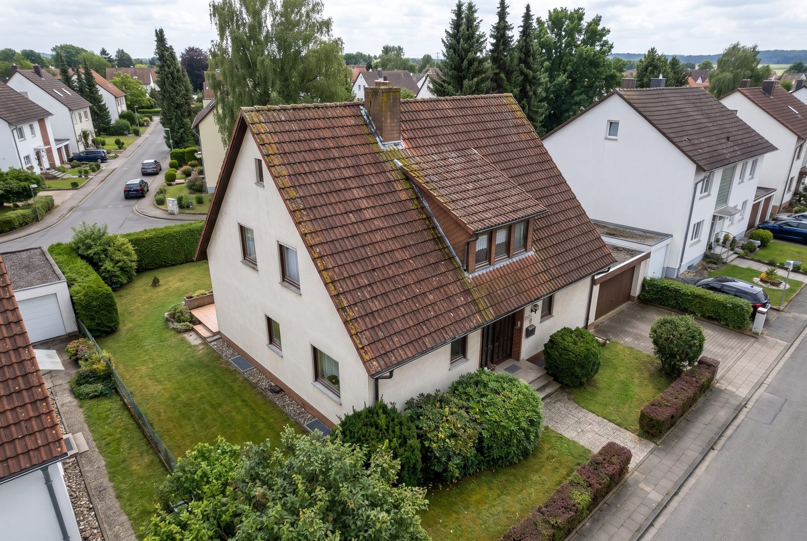 Dasselbe Einfamilienhaus mit vermoostem, rotbraunem Altdach